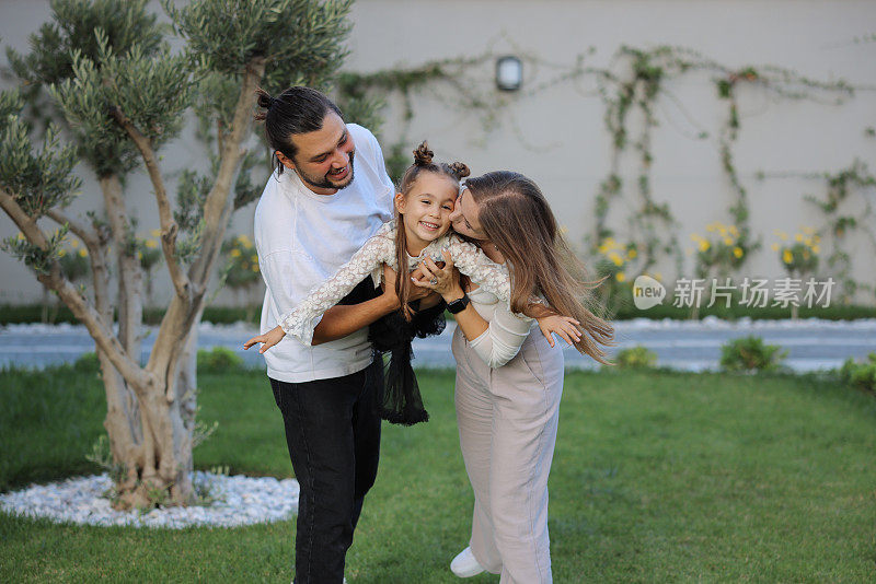 幸福的家庭和女儿在绿色的花园里玩耍