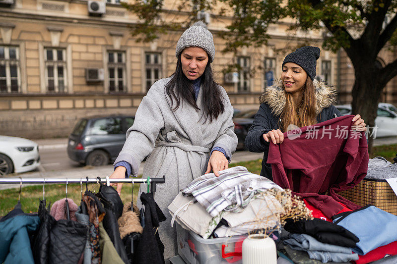 两个女性朋友在街头跳蚤市场挑选衣服