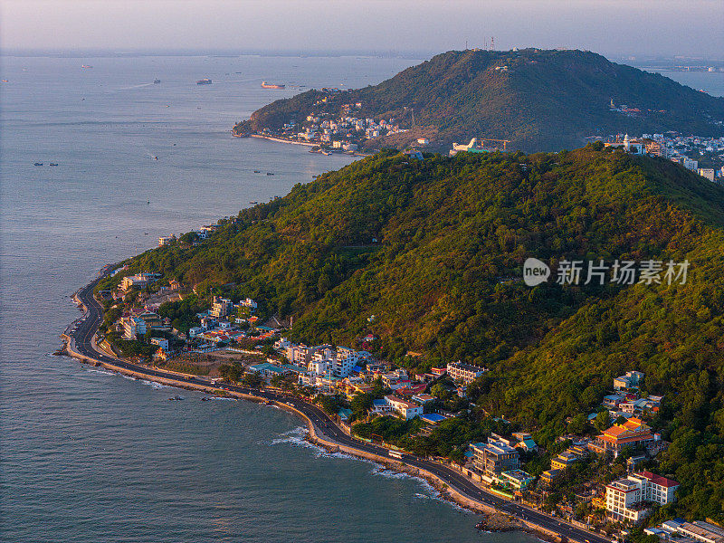 从上面俯瞰云头海岸全景，海浪、海岸线、街道、椰子树、越南Nho山后面的基督国王雕像