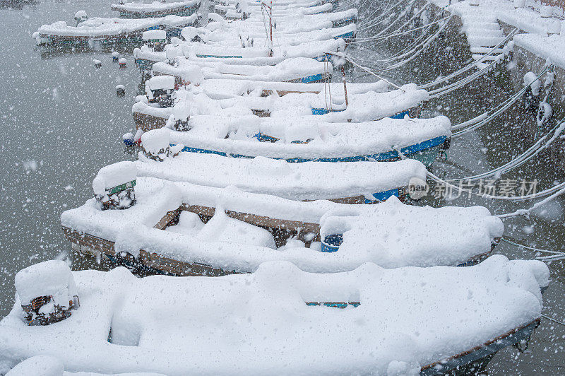 大雪过后，小木船停泊在渔港里