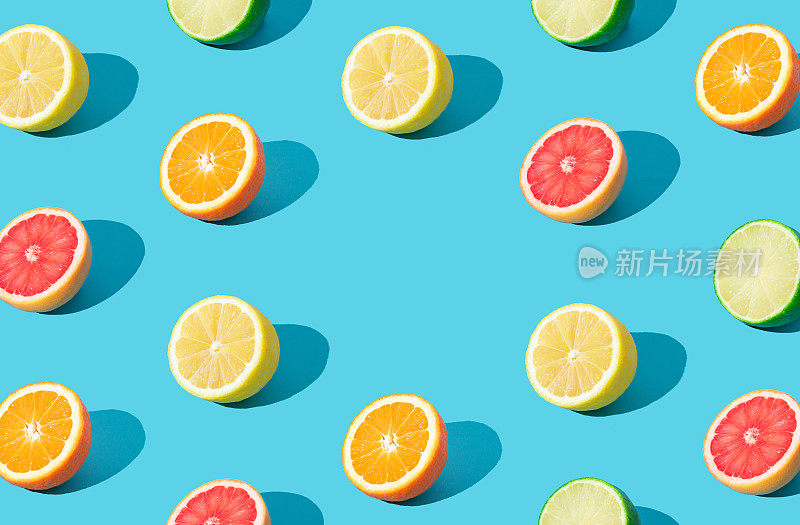 彩色的阳光水果图案由红色葡萄柚，橙子，酸橙和柠檬片在浅蓝色的背景与复制空间。最小的夏季概念。有创意的食物点子。柑橘类水果美学。