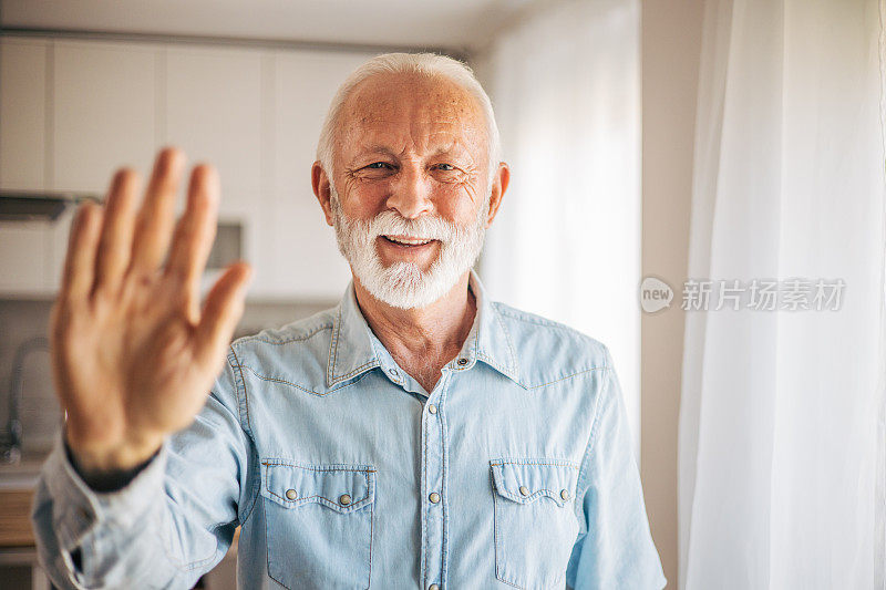 老人对着镜头友好地微笑着，挥手问好、嗨、问候或再见
