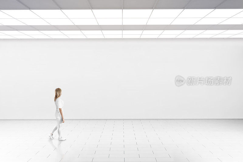 一个女人走进博物馆的画廊，墙上一片空白。