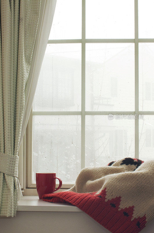 窗台上放着针织毯子和一杯热饮
