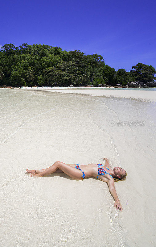 微笑的女人在莫伊安岛的浅水日光浴。