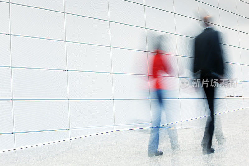 男人和女人走过白色走廊，模糊的运动