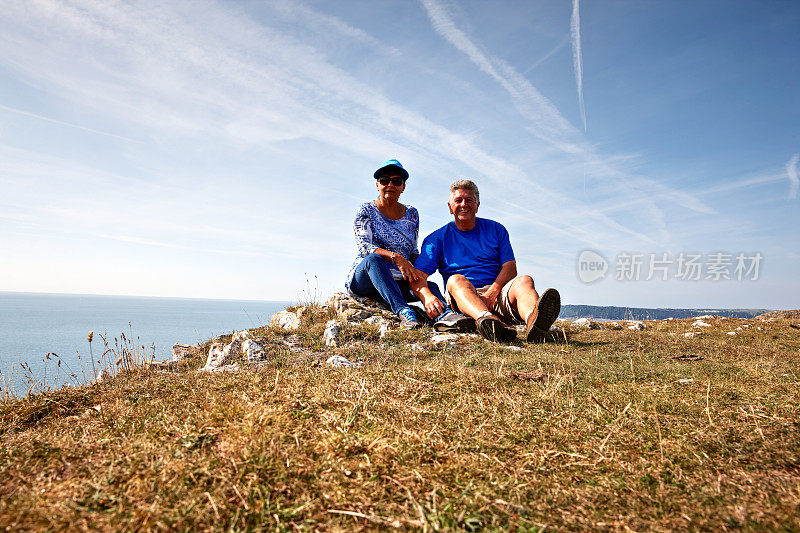 一对成熟的微笑情侣在海岸岬角休息