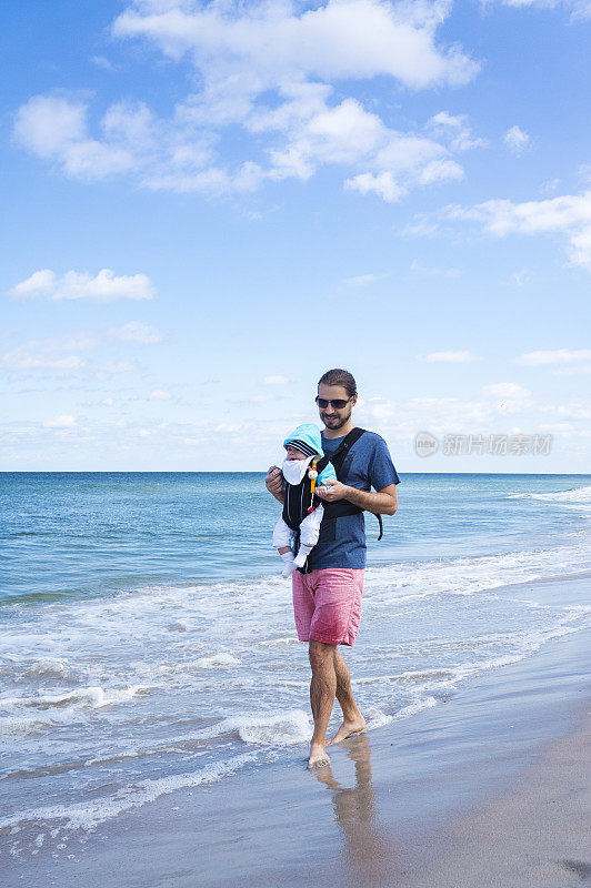 一个男人抱着婴儿车在海滩上散步