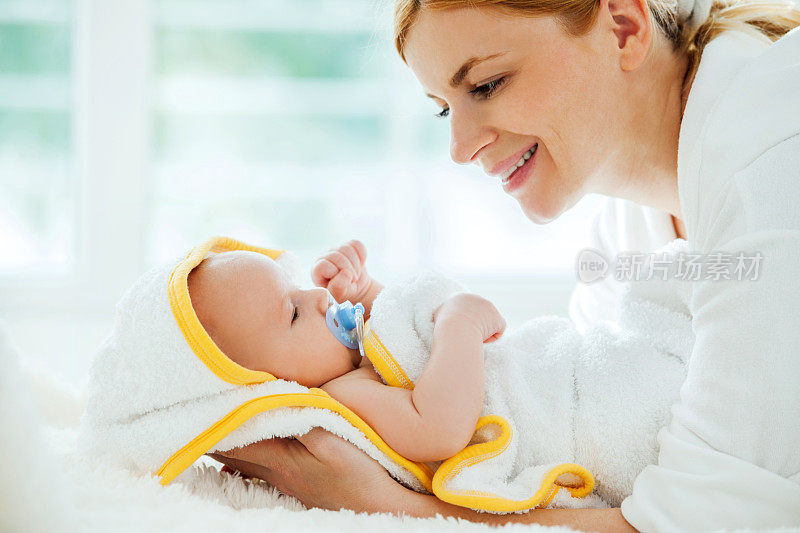 母亲抱着用毛巾裹着的干净男婴。