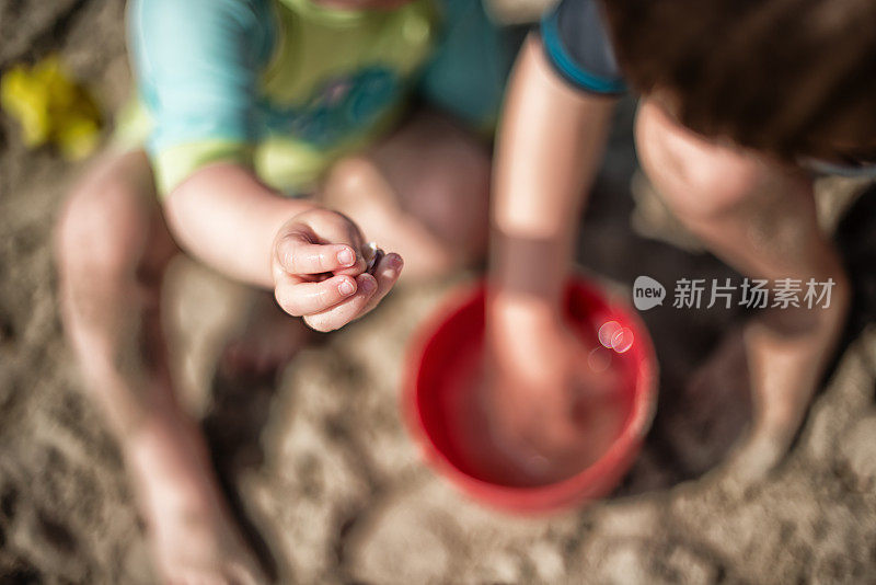 孩子们拿着水桶和水在海滩上玩耍