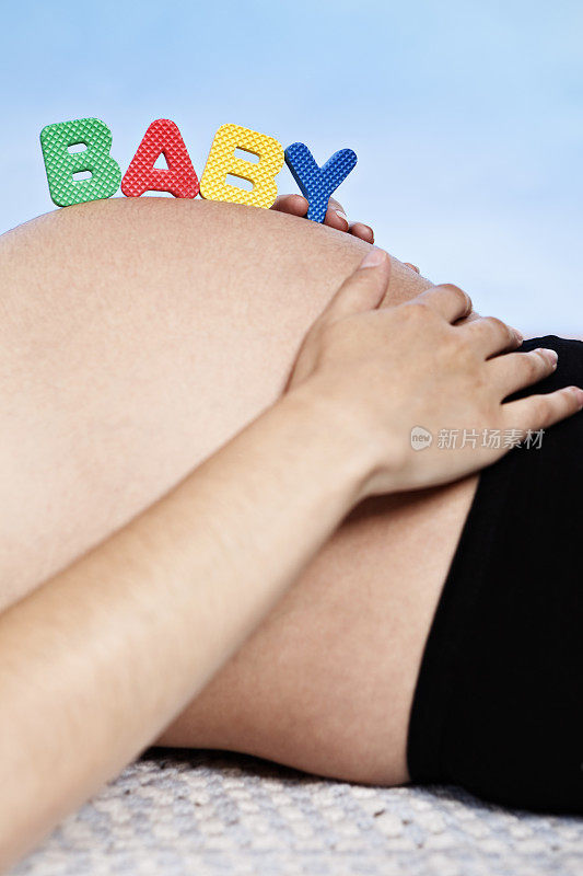 怀孕的肚子上的婴儿字母