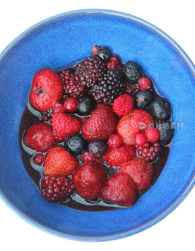 蓝色的盘子与解冻的夏季水果浆果在果汁