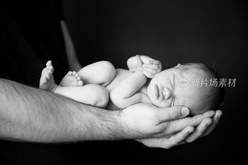 一位父亲的手抱着他刚出生的婴儿