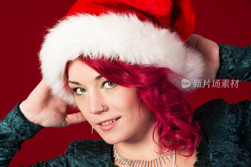 粉红头发的圣诞精灵双手放在帽子上。