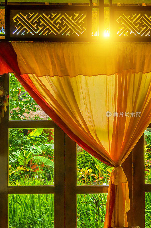 热带花园前的橙色窗帘