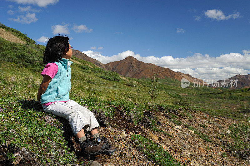 年轻的徒步旅行者坐下来，欣赏阿拉斯加的风景