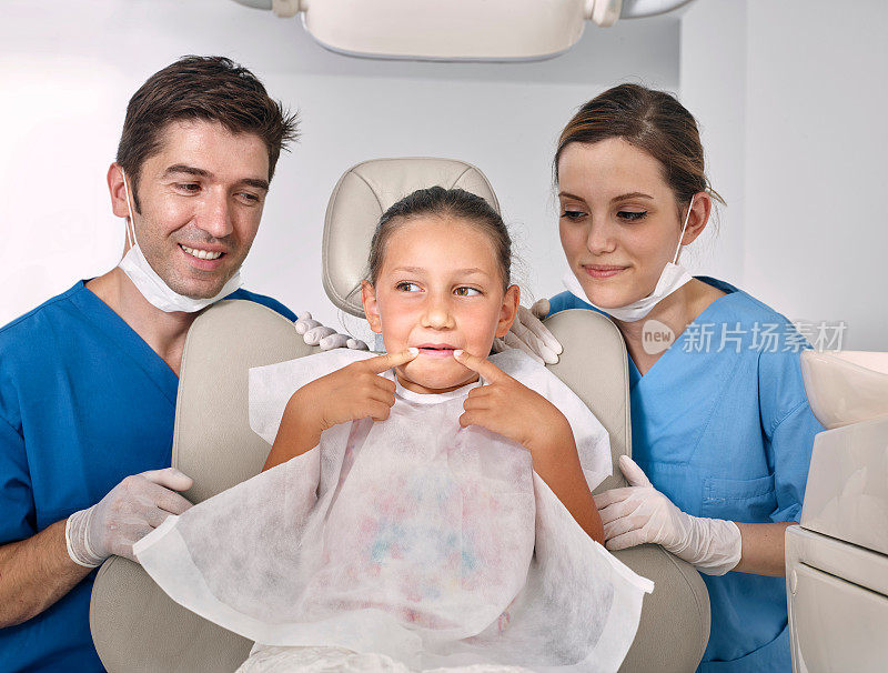 牙医兼助理检查小女孩的牙齿