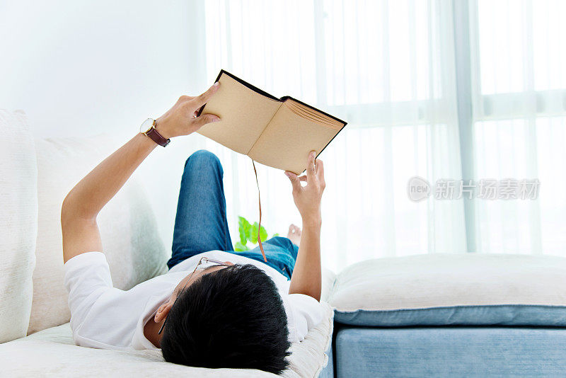 一个年轻的亚洲人在家里看书