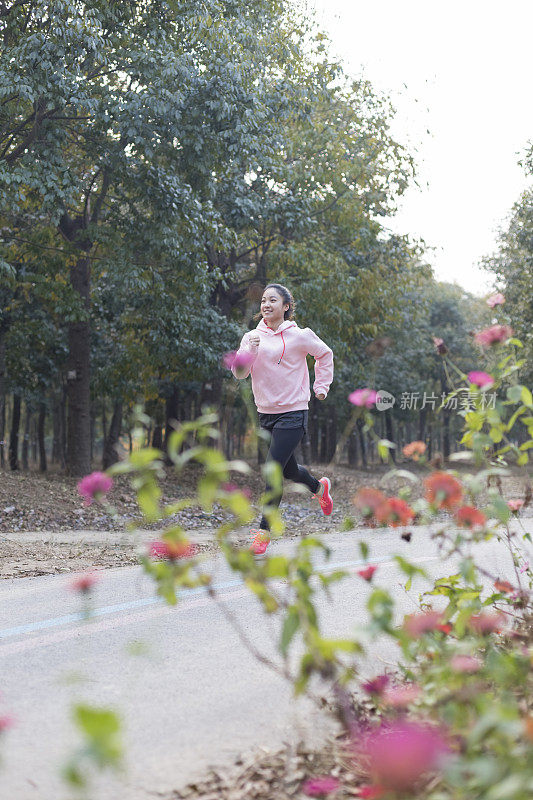 年轻女子在柏油路上伴着音乐奔跑