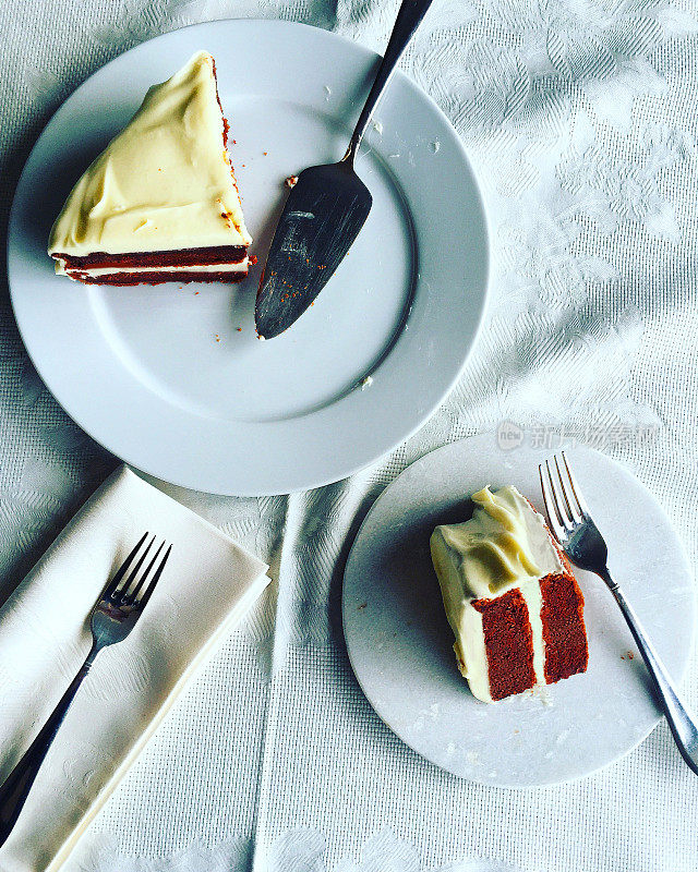 红丝绒蛋糕片放在白色和刀叉上