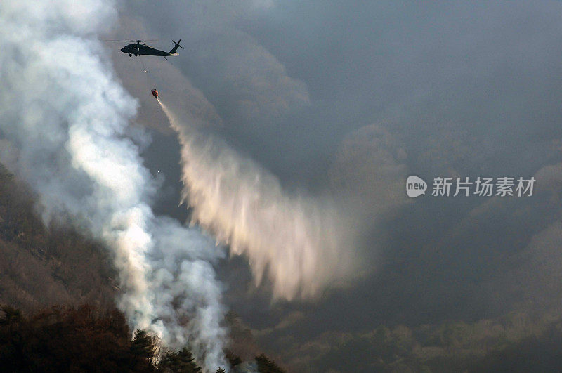 一架军用直升机喷水灭火。