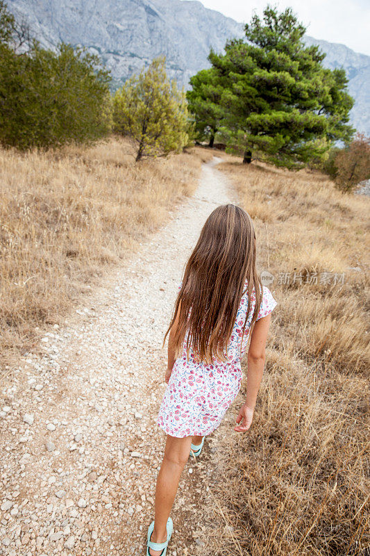 后视图的年轻女孩度假在克罗地亚探索海岸线田野