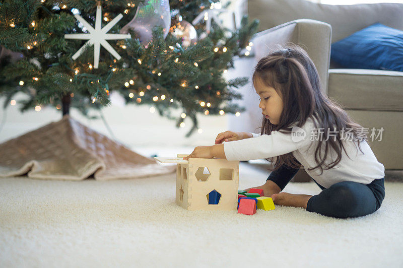 小女孩在圣诞树前玩积木