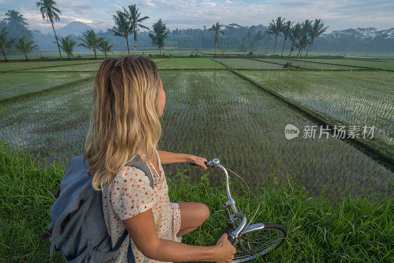 印度尼西亚，一名年轻女子骑着自行车停下来欣赏稻田