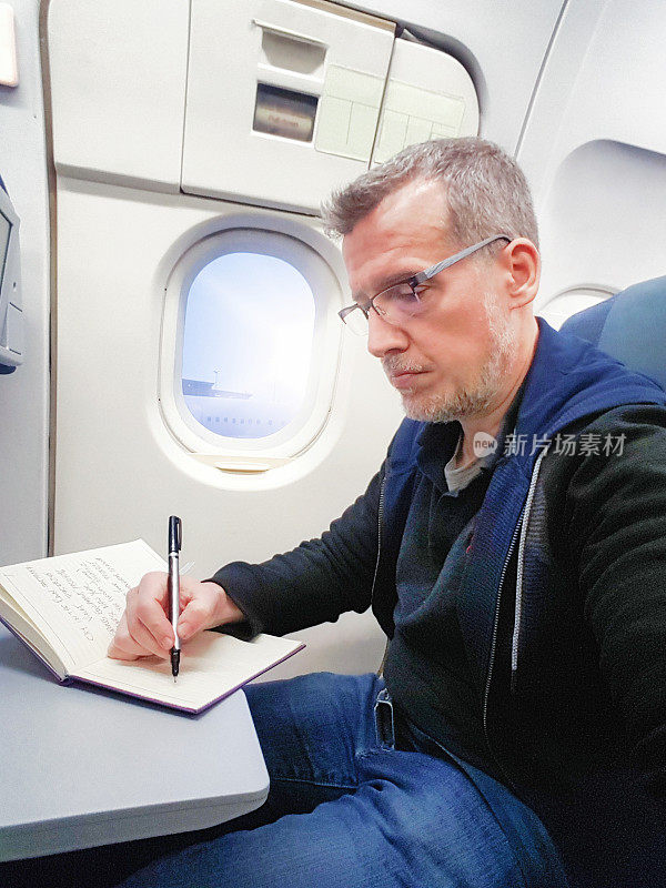 一个成熟的男人在飞机上写笔记本