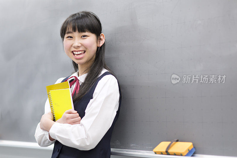 女学生拿着笔记本在黑板前