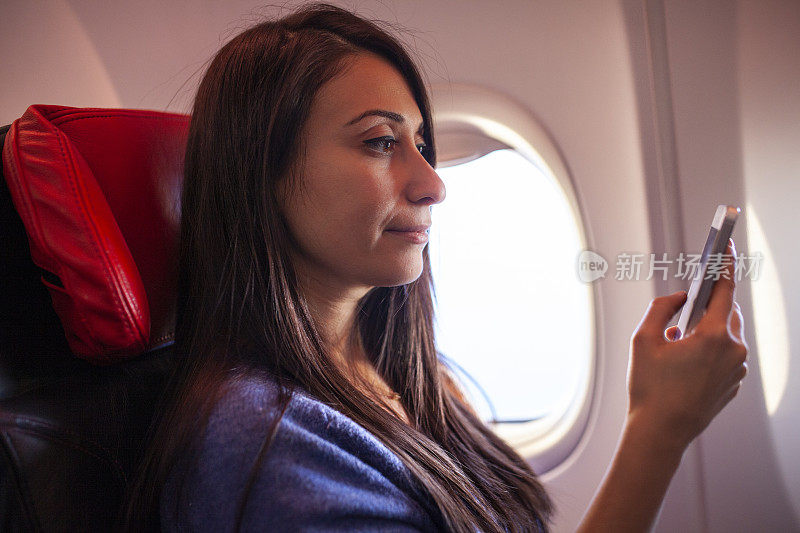 在飞机上用智能手机的女人