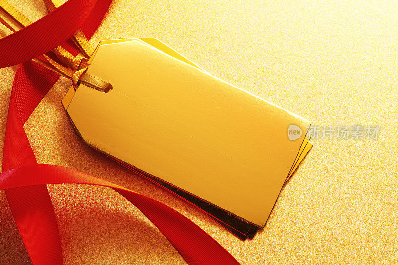 红色丝带缠绕着金色的金属礼品标签