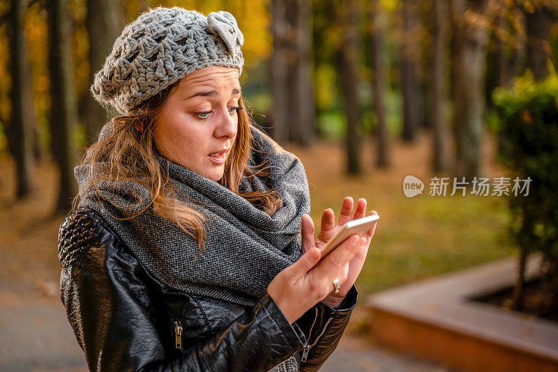 惊讶的女孩在户外用她的智能手机