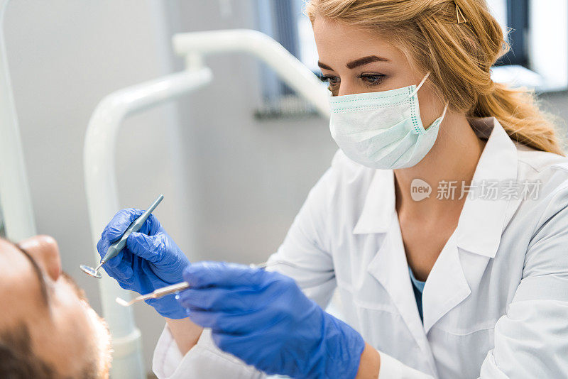 年轻女牙医正在检查病人的牙齿