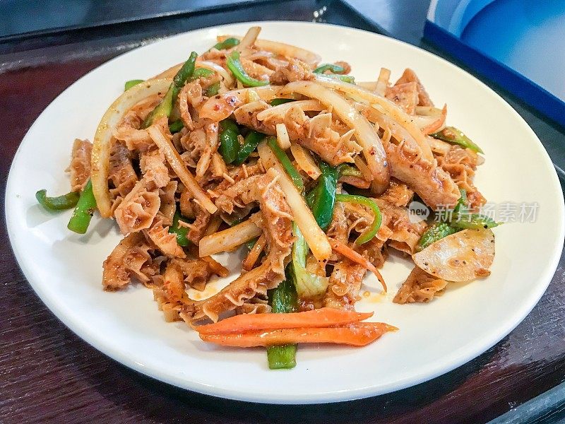 中式炒牛肚配胡萝卜、洋葱、青椒，盛在白瓷盘里，摆上餐桌