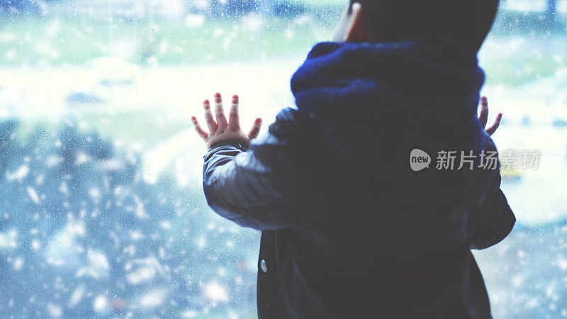 小男孩在一个下雪天望着窗外