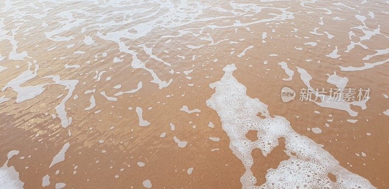 泡沫状的白色海浪拍打着海滩