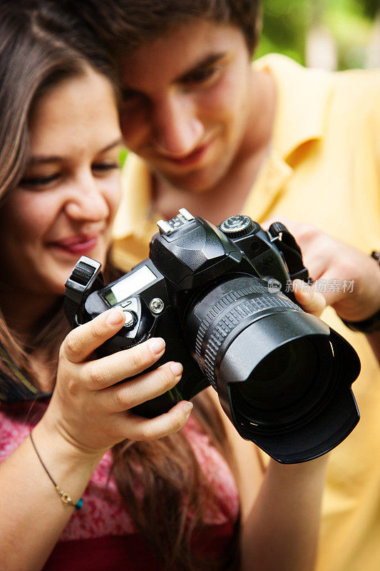 一对年轻夫妇看着相机拍下的照片