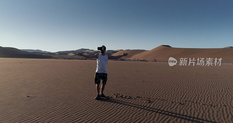 纳米比亚的沙丘上张开双臂的人。探索虚拟现实