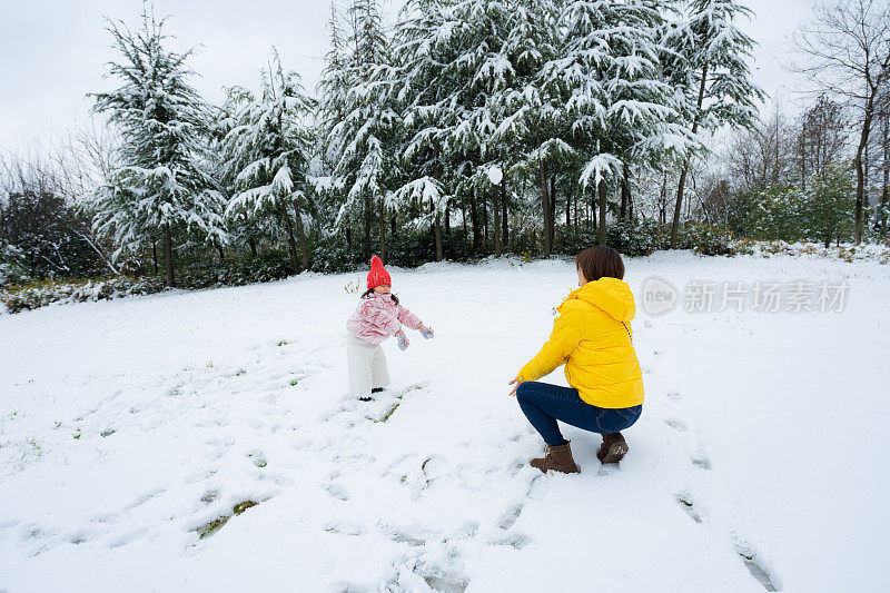 一个小女孩和妈妈在雪中玩耍