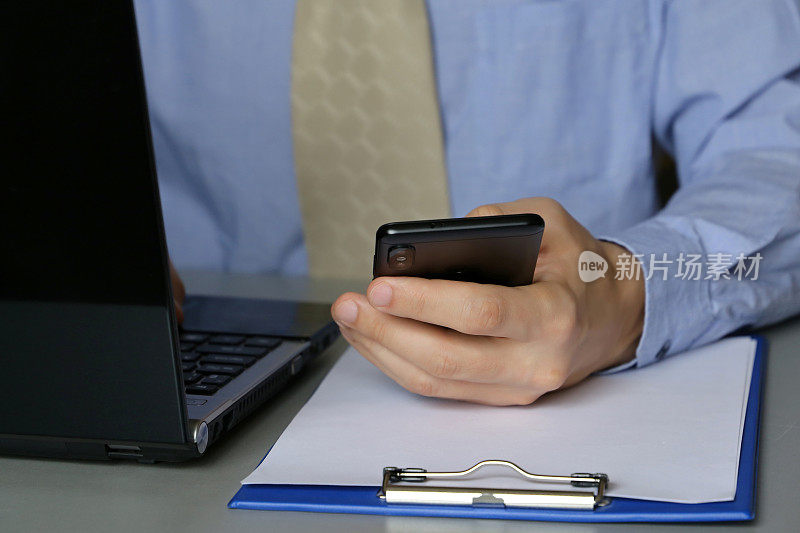 办公室工作，一个穿蓝衬衫打领带的男人坐在桌子前，拿着笔记本电脑