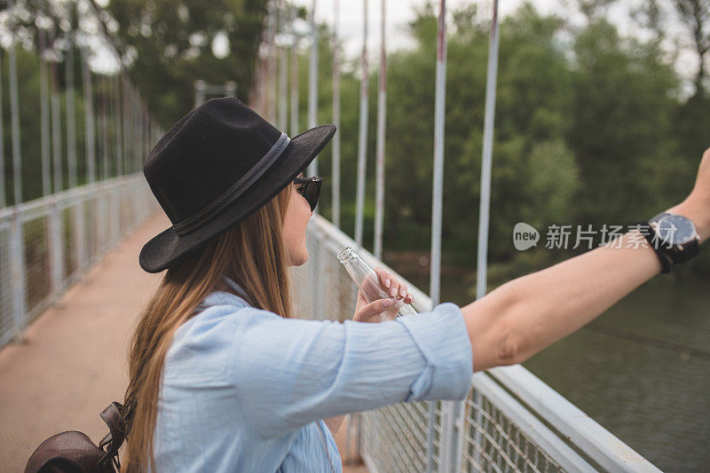 女潮人在桥上喝着酒欣赏着河景