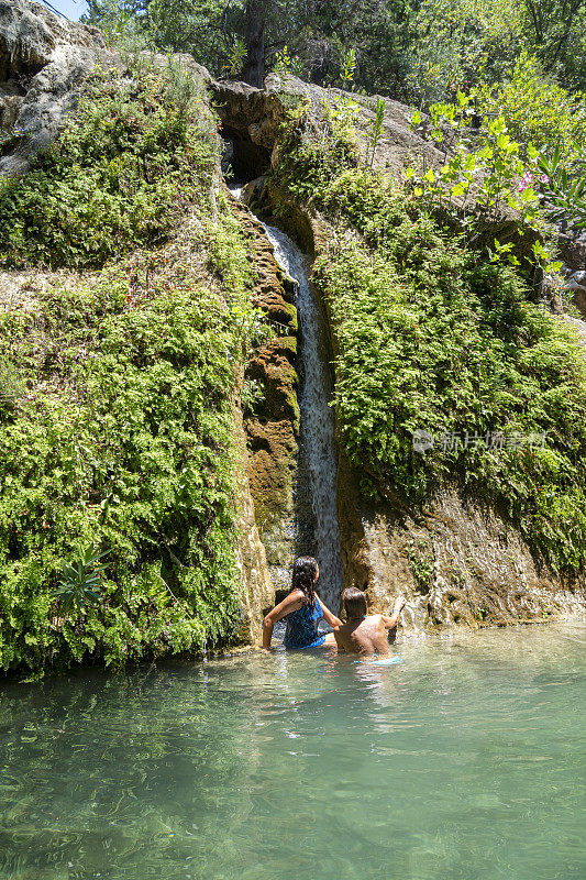 在瀑布中漂浮的女人。奥卢德尼兹卡巴克湾的阿拉德尔瀑布。Fethiye,土耳其。