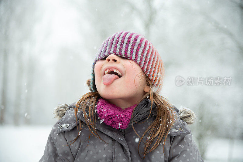 小女孩在雪中玩耍，她试图用她的嘴去接雪花