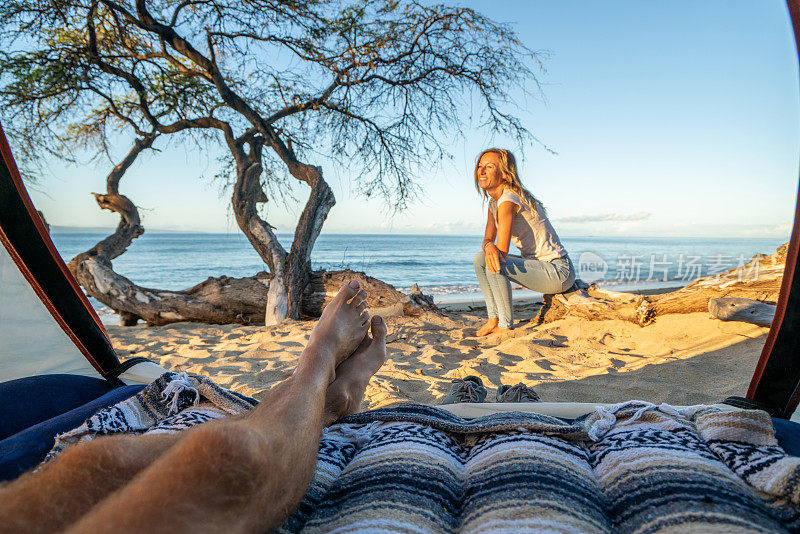 男人的脚从一个帐篷露营在夏威夷的海滩看在他旁边的女朋友的观点