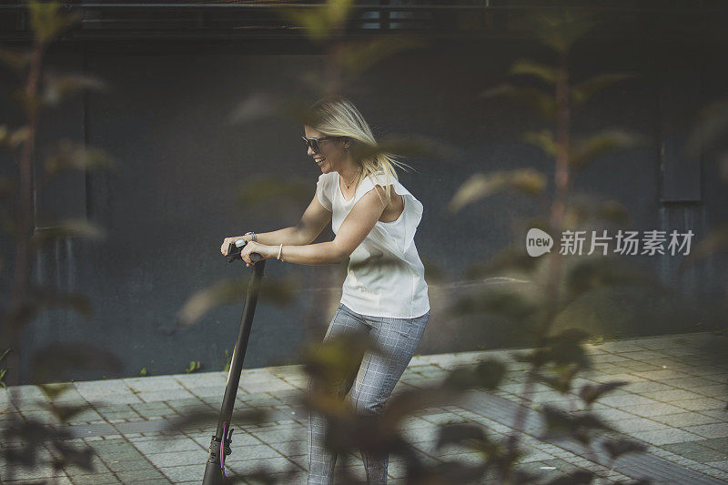 年轻的女商人在城市里骑摩托车