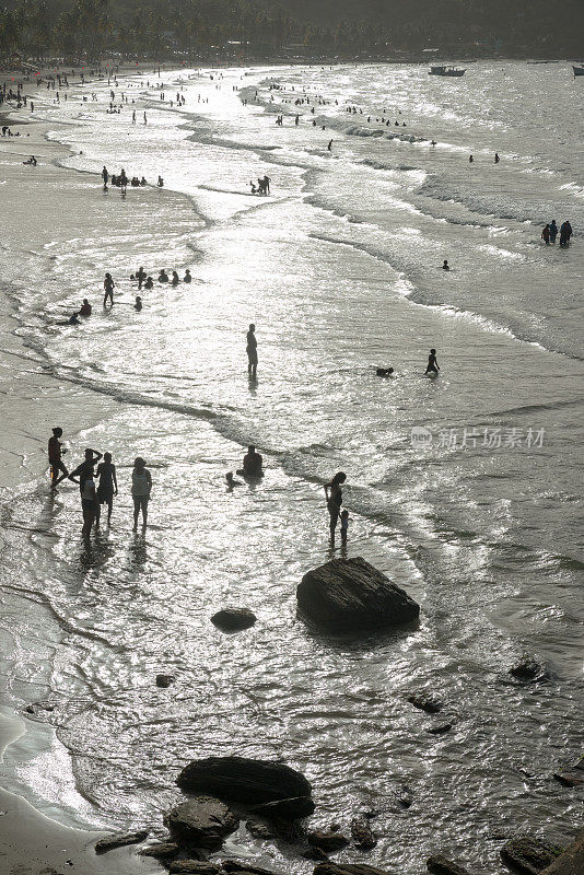 人们在海滩上迎着海浪游泳