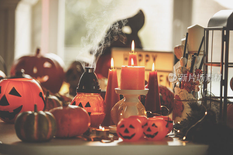 桌上点着的橙色蜡烛和万圣节装饰品的静物画
