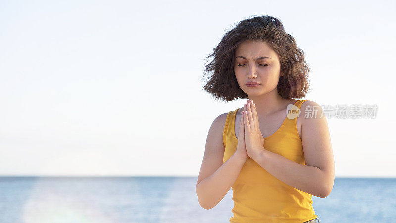 妇女在自然日落背景下祈祷和练习冥想，希望的概念