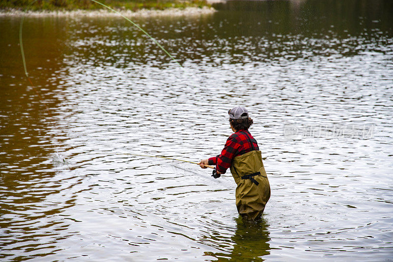 一个年轻的飞鱼渔夫在秋天的河里。